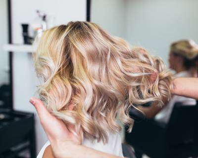 blonde wavy hairstyle in salon with stylist hands showing effortless curls and natural shine