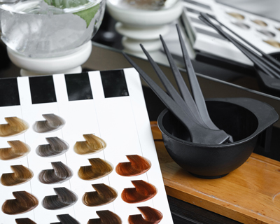 hair color samples with mixing bowl and applicator brushes showing various shades in a salon setting